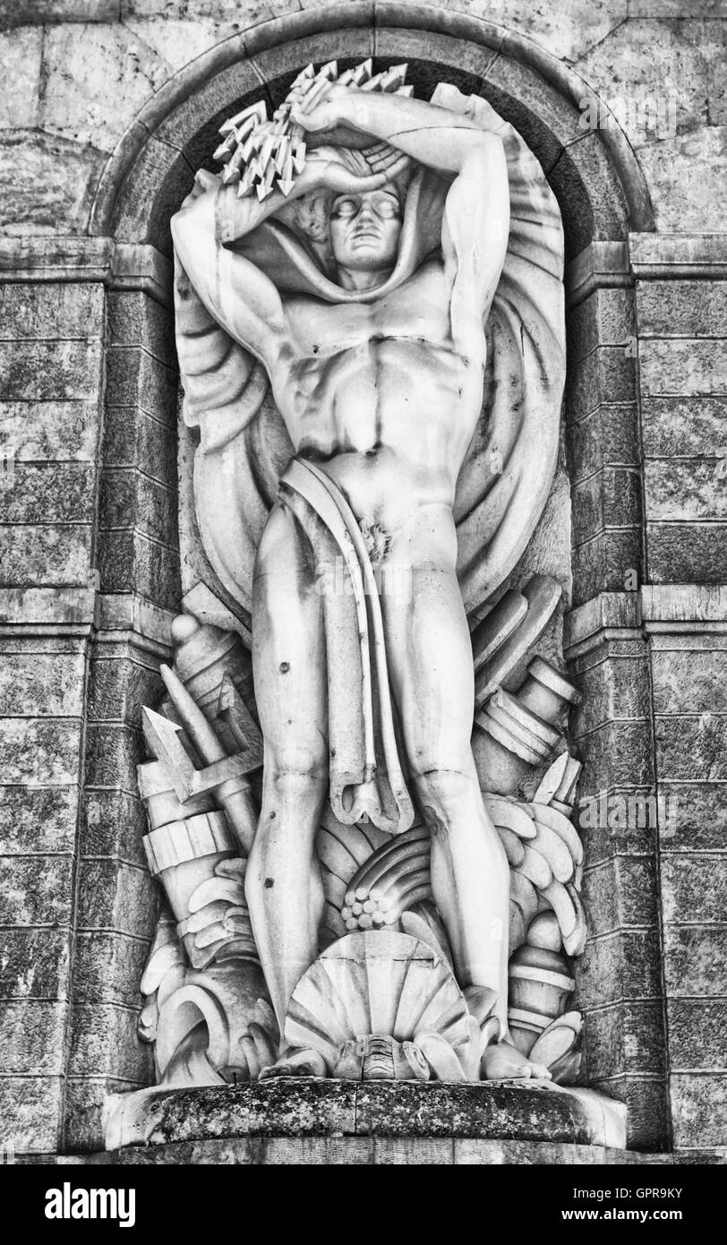 Statue of the god of the waters on the facade of a hydroelectric plant. Stock Photo