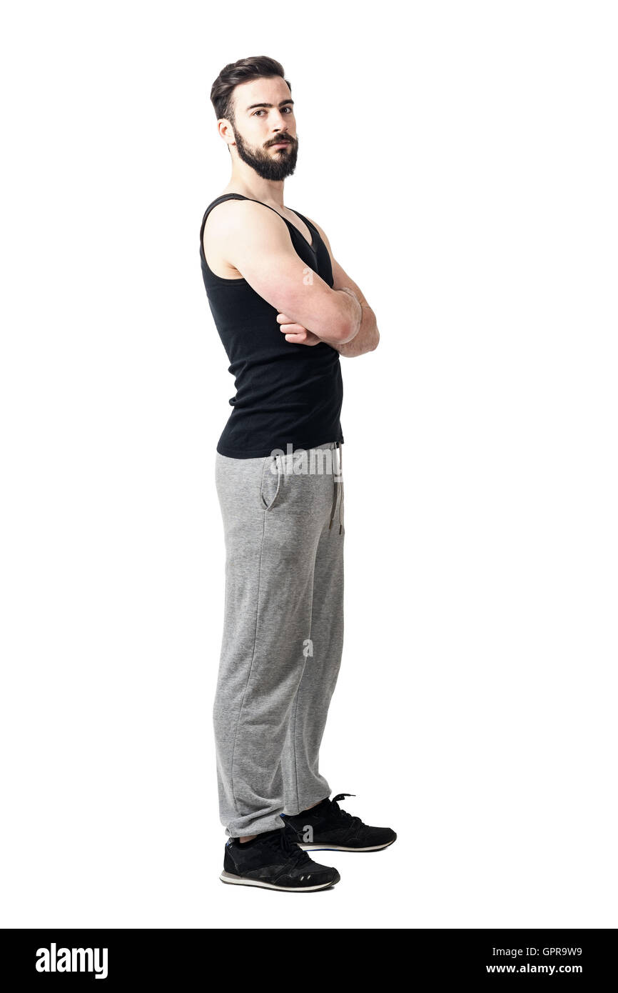 Side view of muscular athlete in tank top with crossed arms. Toned desaturated full body length portrait isolated on white Stock Photo