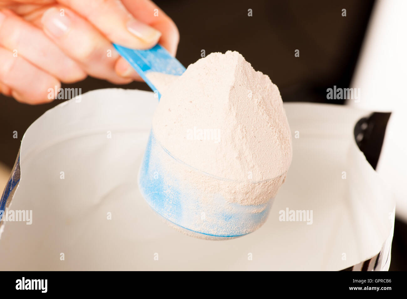 Heaped measuring scoop of whey protein powder with chocolate flavor. Stock Photo