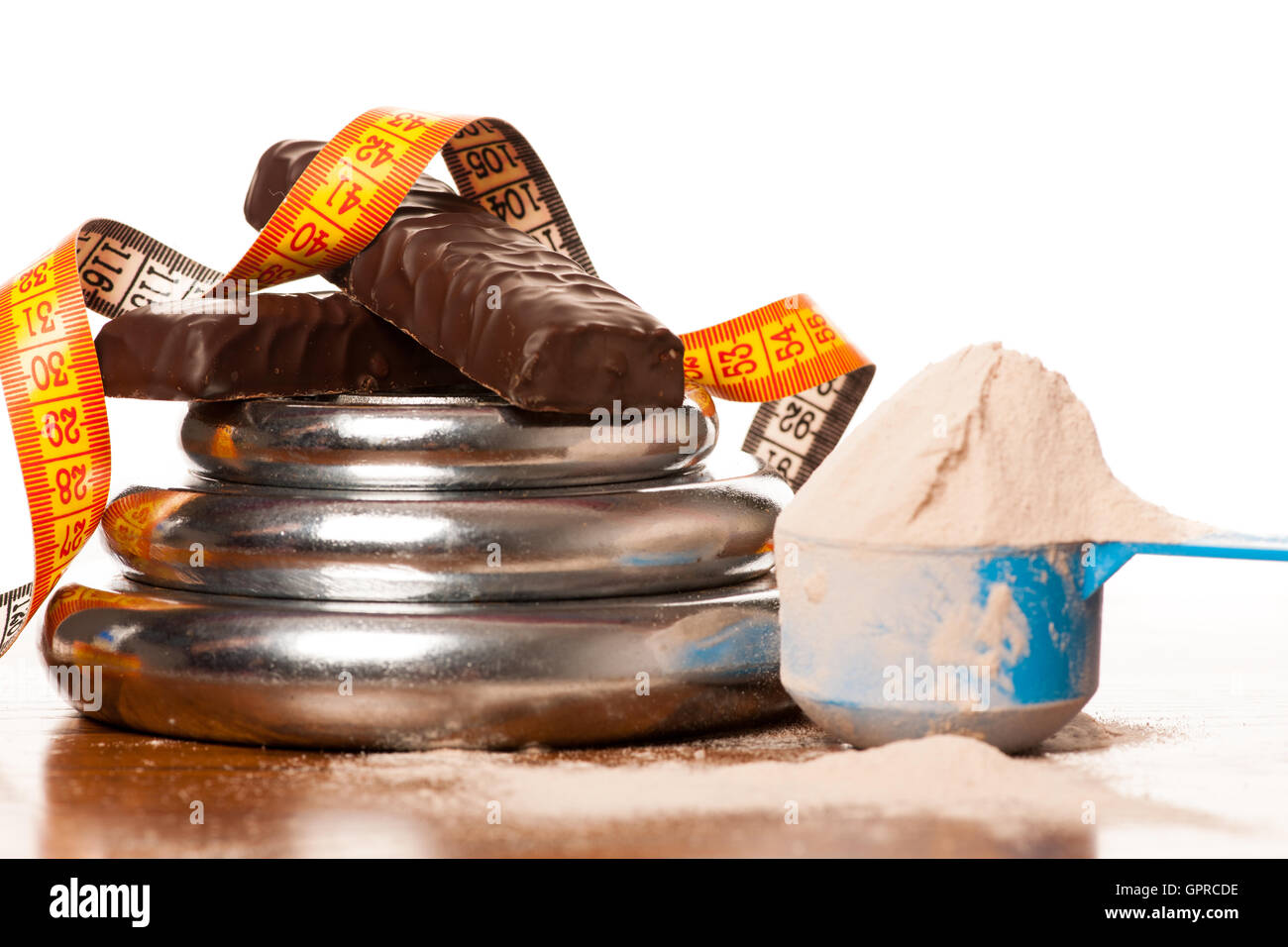 Whey protein powder in measuring scoop, protein bar, meter tape and