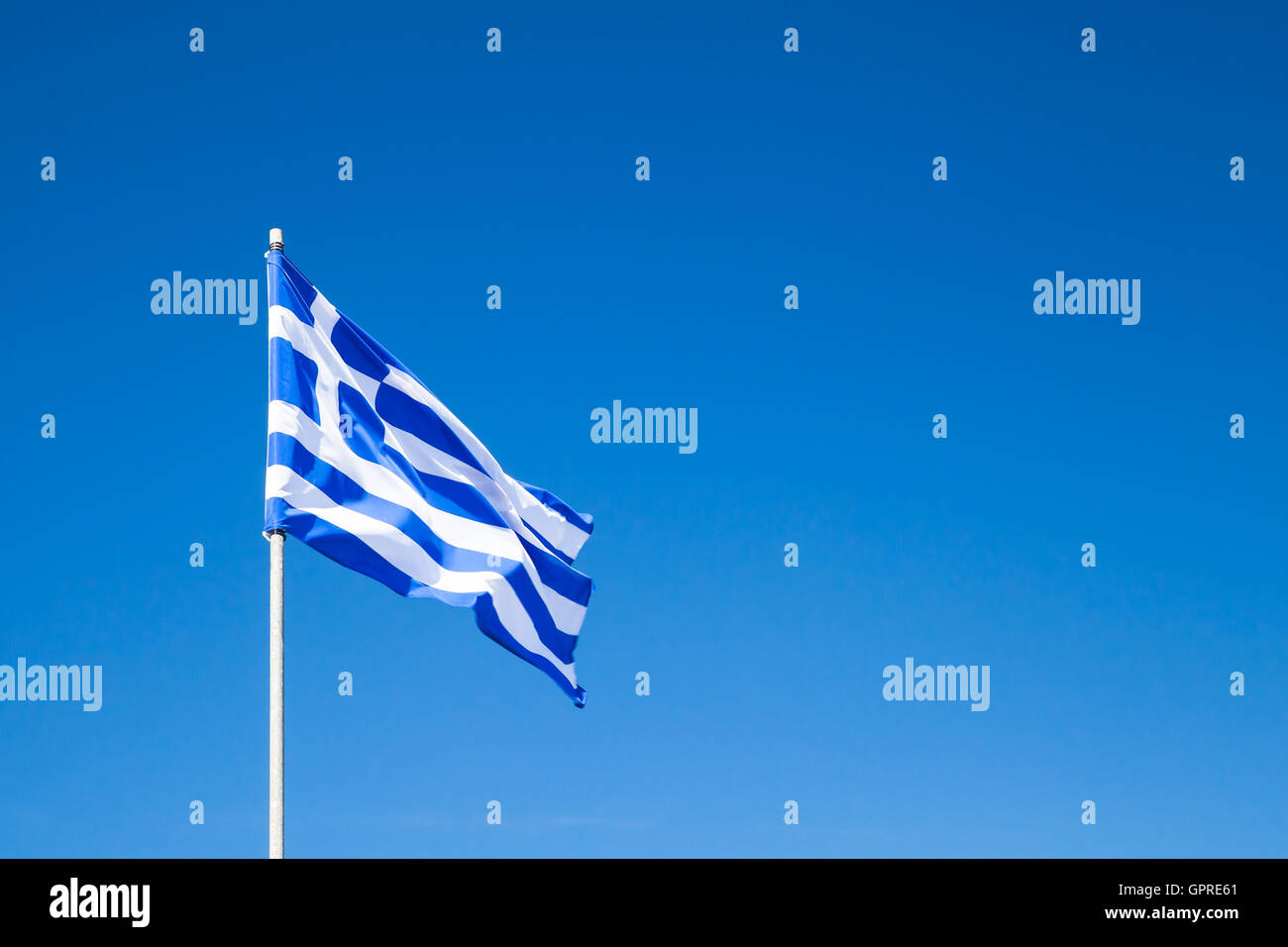 Flag of Greece waving on a flagpole over clear blue sky background Stock Photo