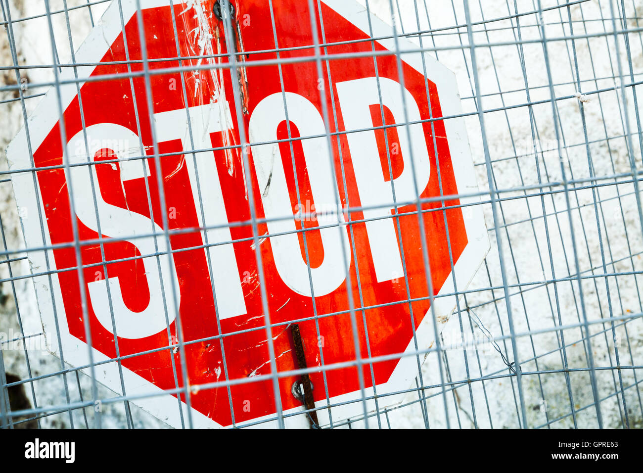 Red stop road sign covered with metal grilles Stock Photo