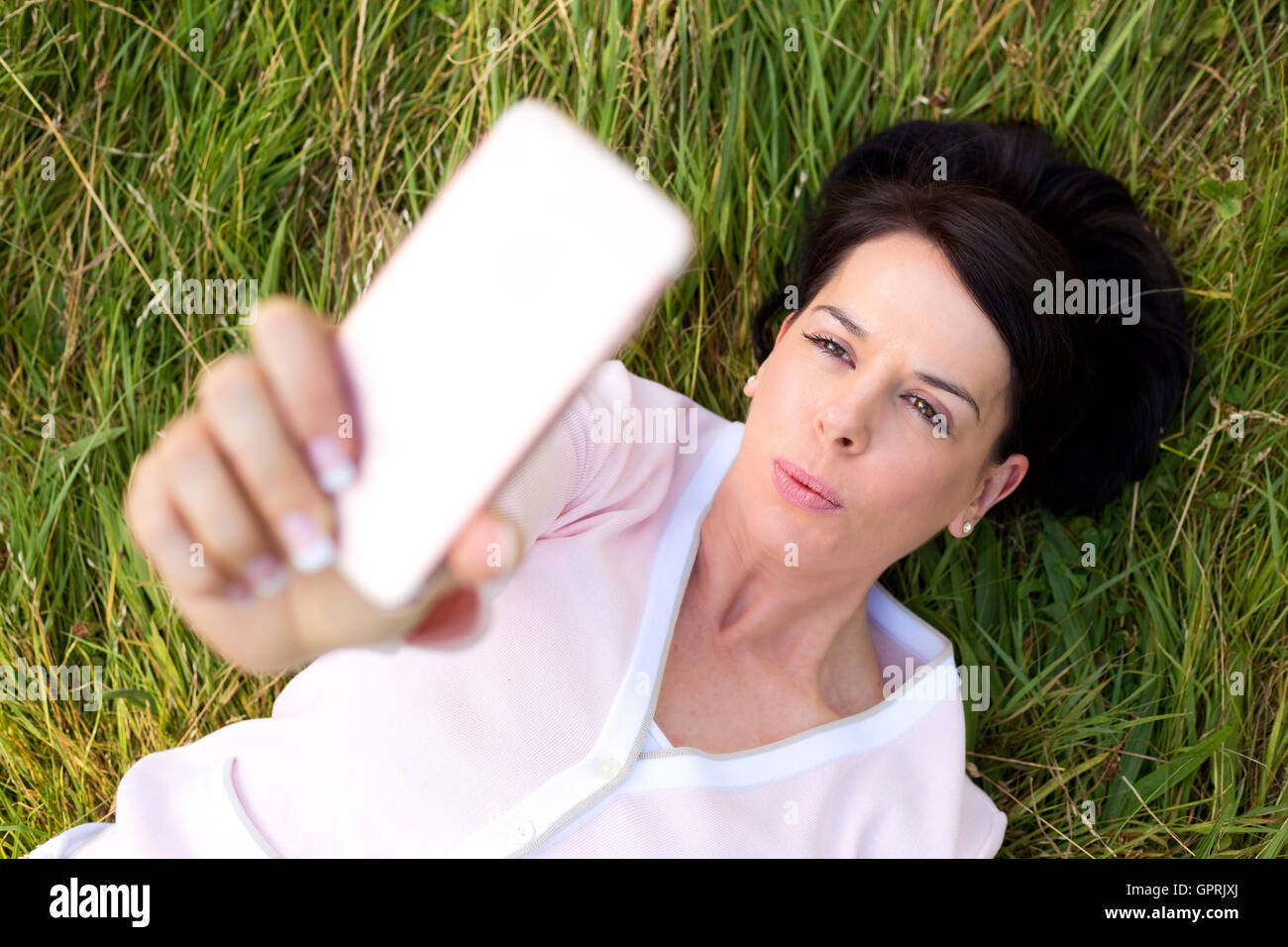 woman lying on the grass taking a selfie Stock Photo