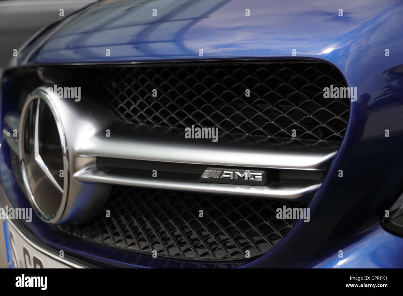 The front end of a blue Mercedes-Benz C63S AMG, showing the grill, the Mercedes-Benz Star and the AMG Logo. Stock Photo