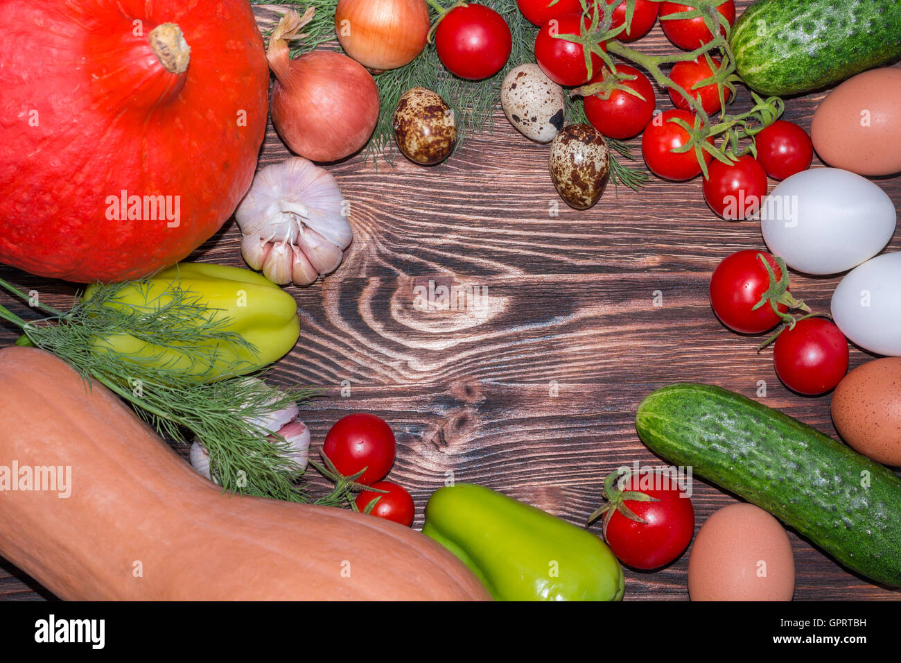 Bright Thanksgiving harvest composition of vegetables onions, cucumbers, peppers pumkin, calabash, tomatoes, garlic, eggs on dar Stock Photo