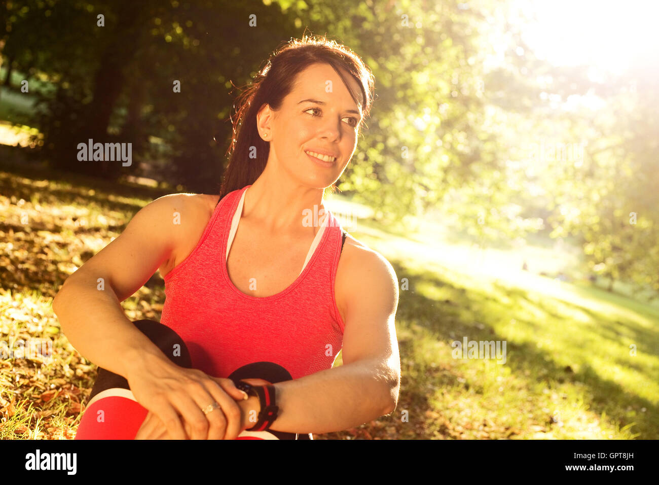 young woman sitting in the park after exercise Stock Photo