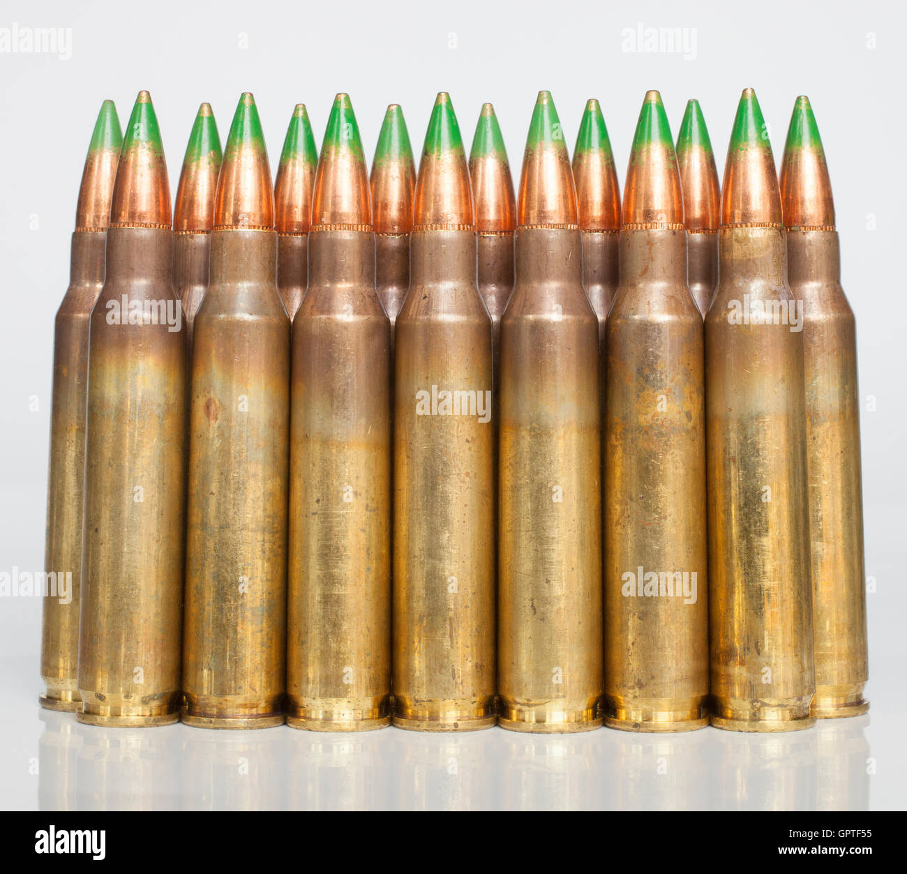 Rifle cartridges with bullets that have a green tip on a white ...