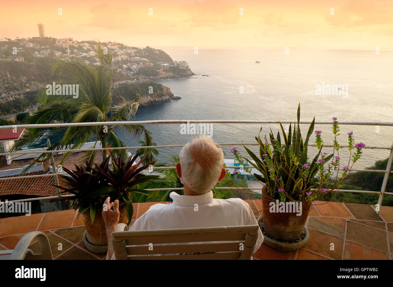Older man looking at ocean from balcony Stock Photo