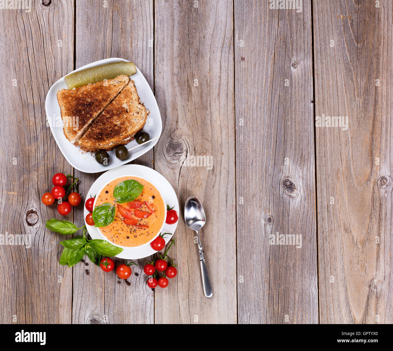 Overhead view of a bowl of fresh creamy tomato soup, tuna sandwich