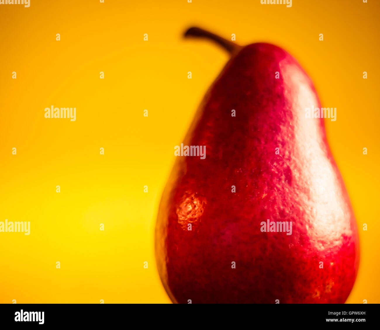 A close up of perfect red Anjou Pear against a yellow background. Stock Photo