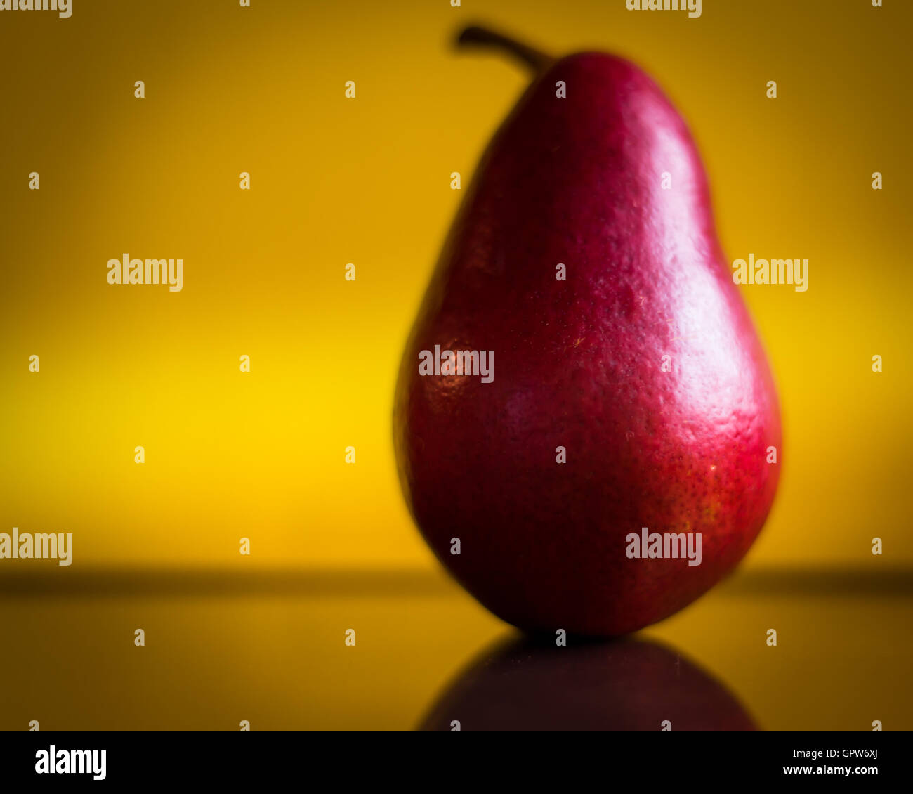 A perfect red Anjou Pear against a yellow background. Stock Photo