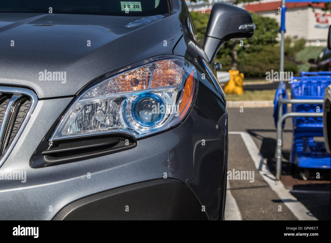 A closeup of a front headlight of an SUV in a store parking lot. Stock Photo