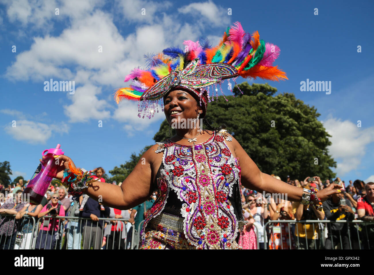 A woman dressed in a brightly coloured feathered headdress dances at the Leeds West Indian Carnival in Leeds, West Yorkshire. Stock Photo