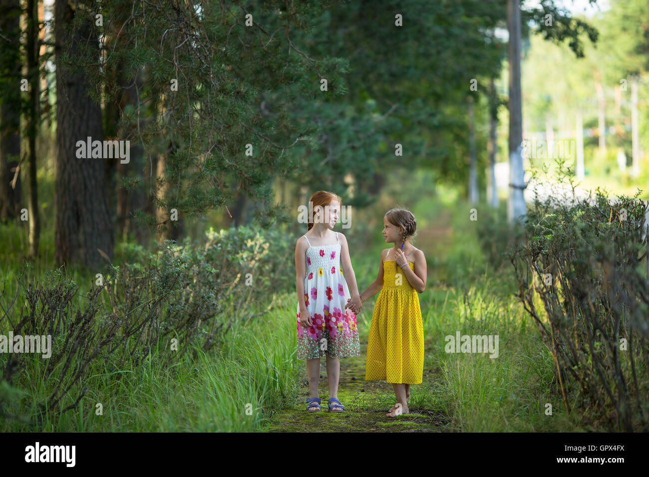 Two little cute girls go and talk in the Park. Stock Photo