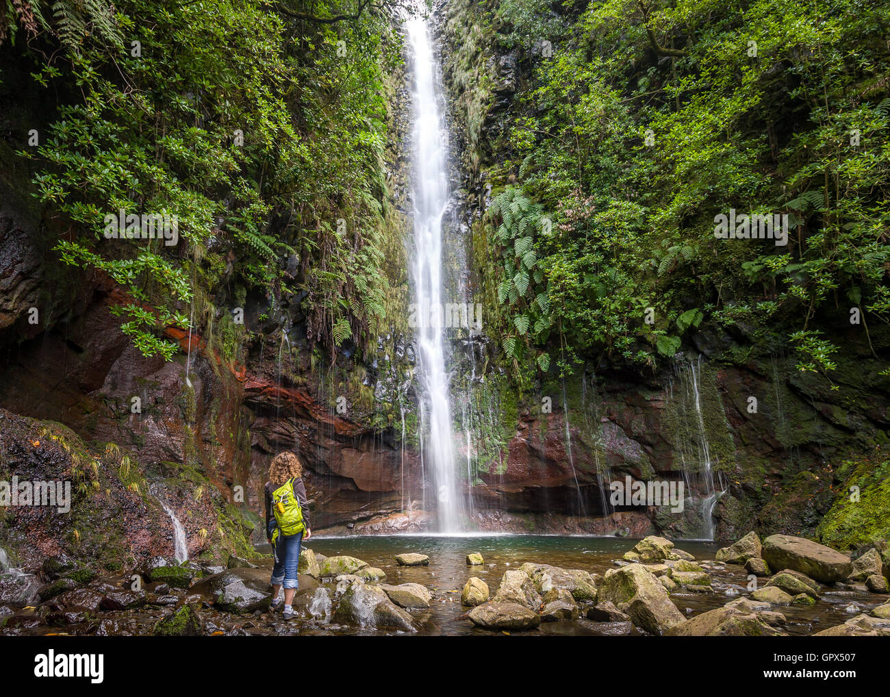 Big waterfall and woman hiker at levada 25 fountains in Rabacal, Madeira island Stock Photo