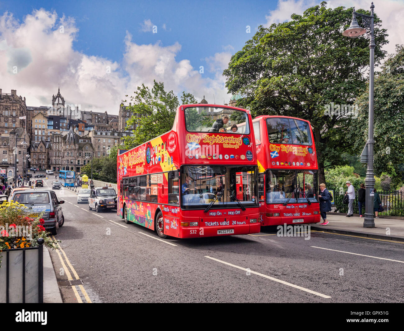 Two City Sightseeing tour buses at a bus stop on Waverley Bridge, Edinburgh, one overtaking the other, Scotland, UK Stock Photo
