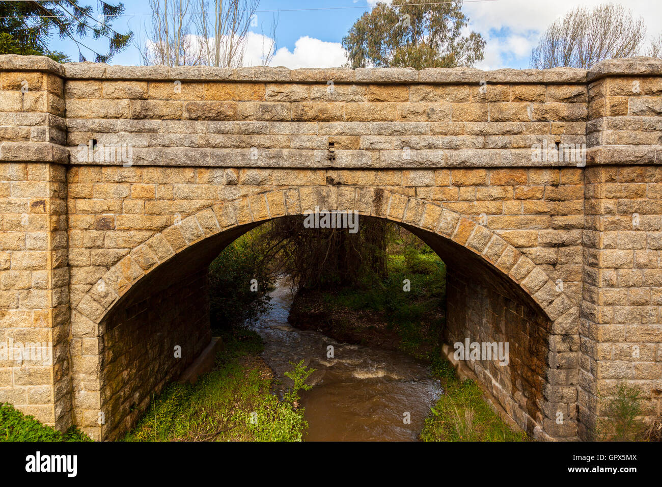 Stone bridge, hand carved stone bricks, water flowing, arched structure Stock Photo