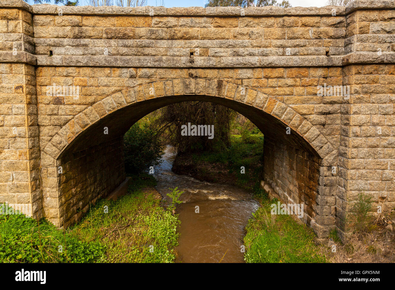 Stone bridge, hand carved stone bricks, water flowing, arched structure Stock Photo