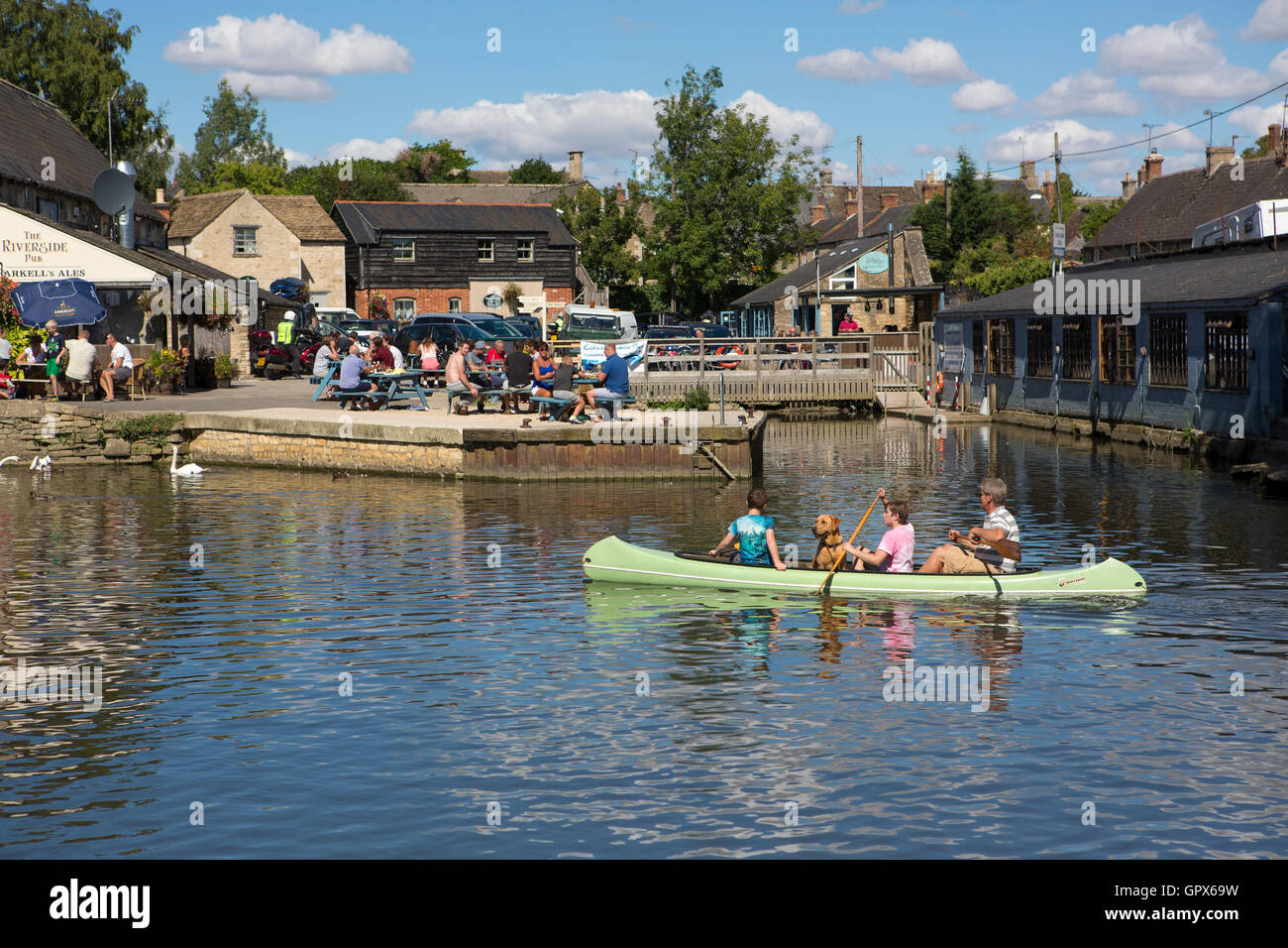 A canoe with family and dog paddling down the River Thames at Lechlade