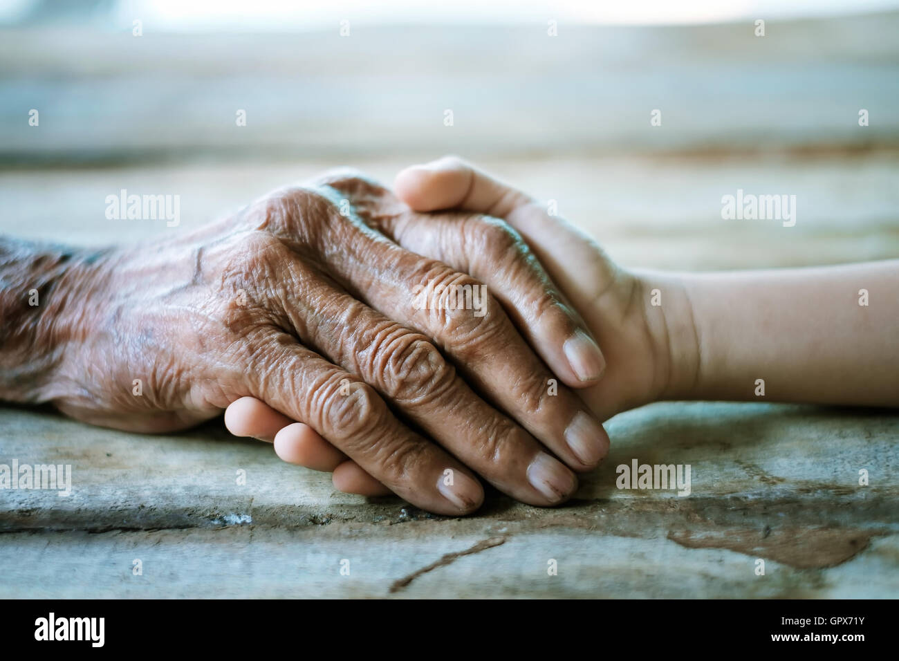 old man and a kid holding hands together on the wood table Stock Photo ...
