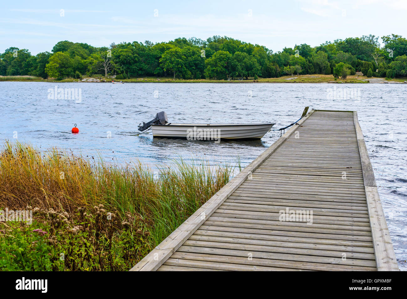 Small open motorboat or rowboat moored at wooden pier with archipelago in background. Skavkulla outside Karlskrona in Sweden. Stock Photo