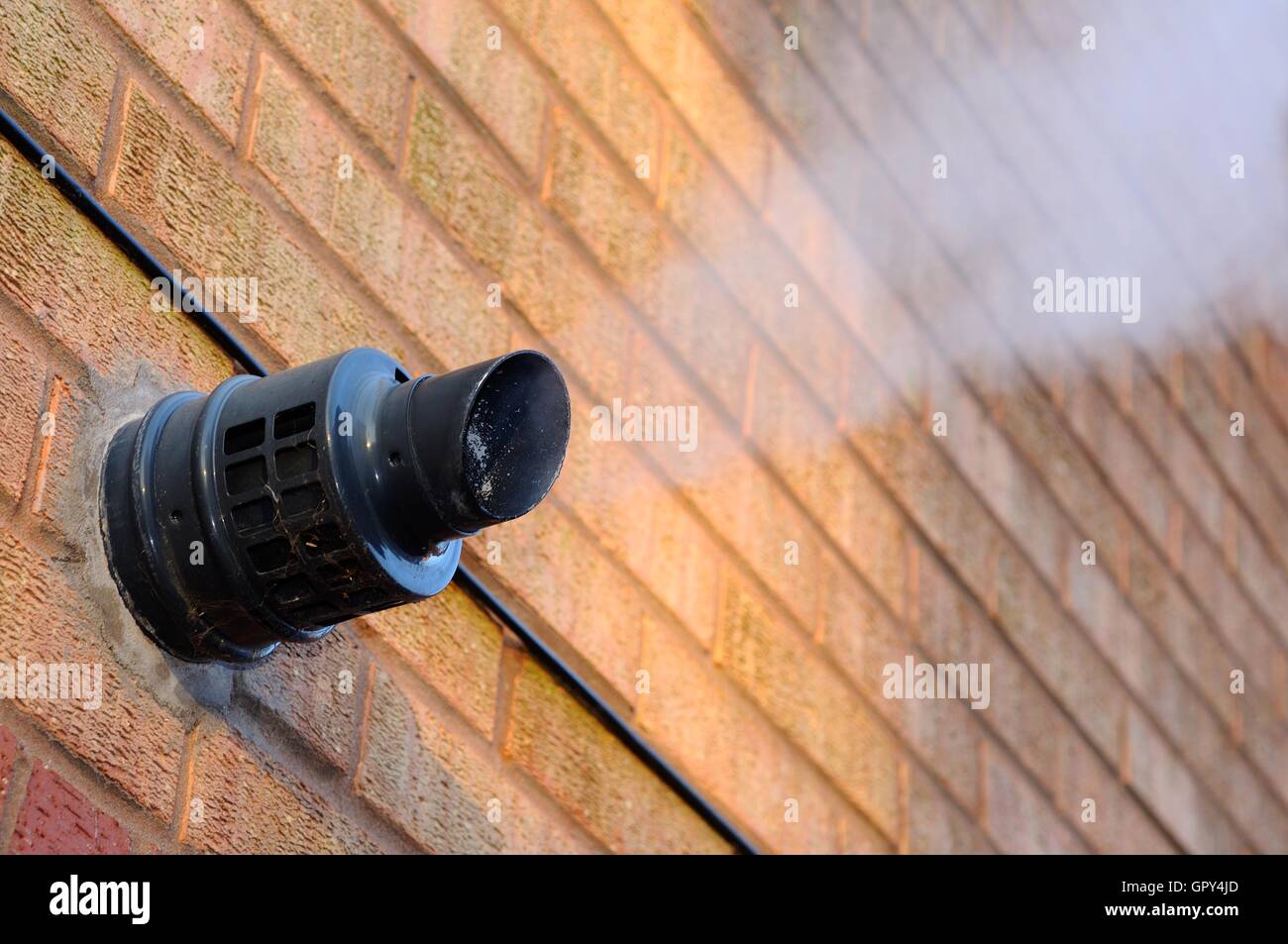 Steam coming out of a central heating flue on a house wall, England, UK