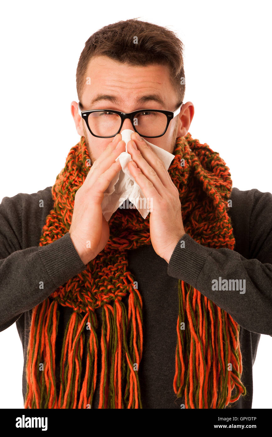 Man with flu and fever wrapped in scarf sneezing into handkerchief isolated over white. Stock Photo