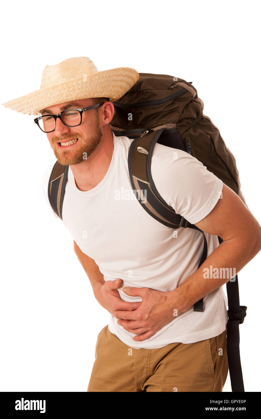 Traveler having stomach ache, nausea wearing straw hat, white shirt and backpack. Isolated over white. Stock Photo