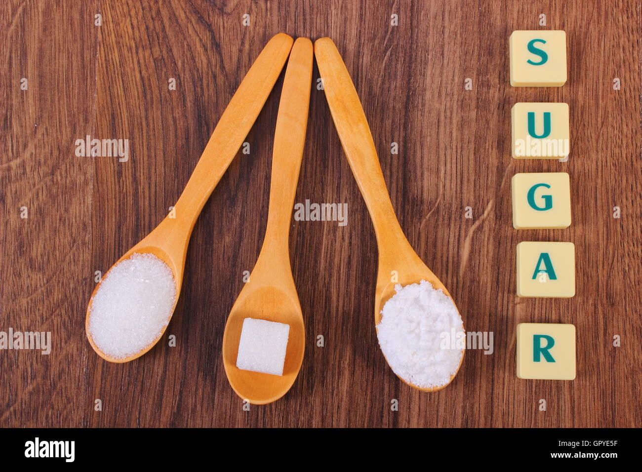Sugar cube, granulated and powdered sugar on wooden spoons, ingredient for cooking or baking