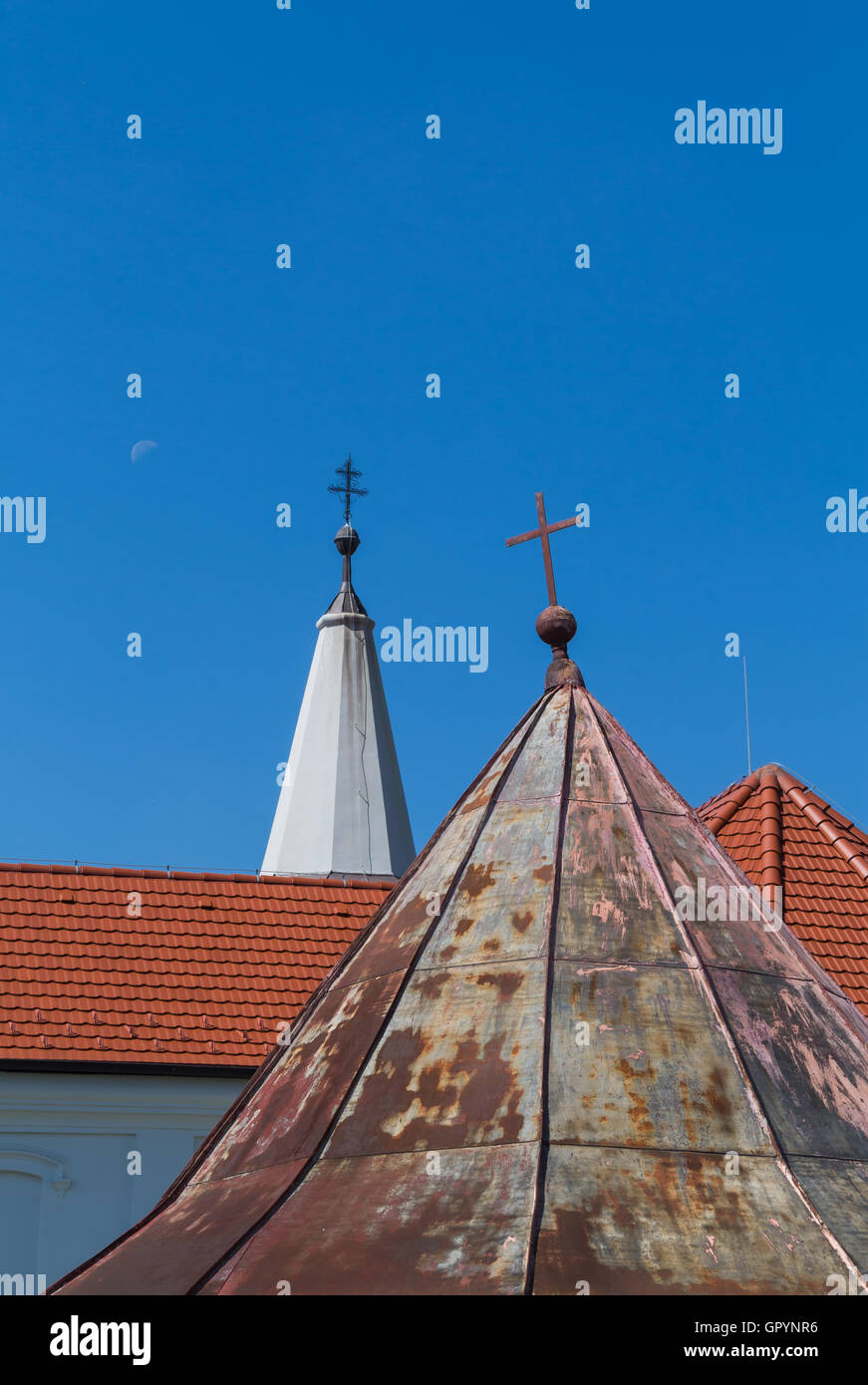 Older and new parts of the roofs of the church of Saint Peter and Paul in Cifer, Slovakia. Two crosses on the top of the towers. Stock Photo
