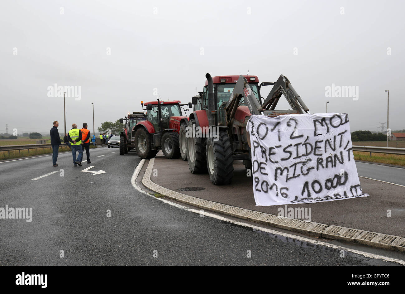 Tractors slow down traffic on a road near Calais, France, as part of a campaign for the Jungle migrant camp to be demolished. Stock Photo