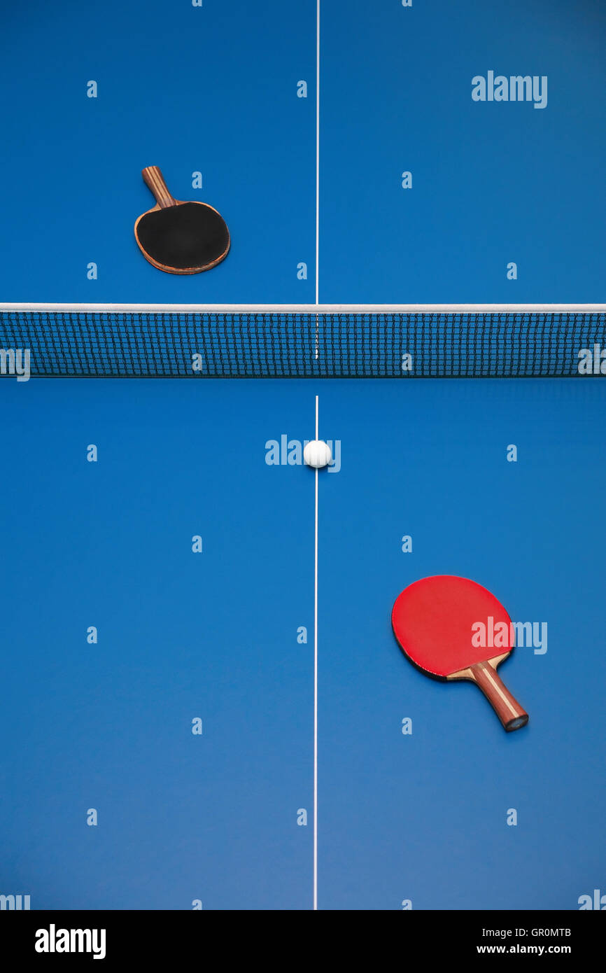 Rackets for blue table tennis of red and  black color and a ball on a tennis table, view from above Stock Photo