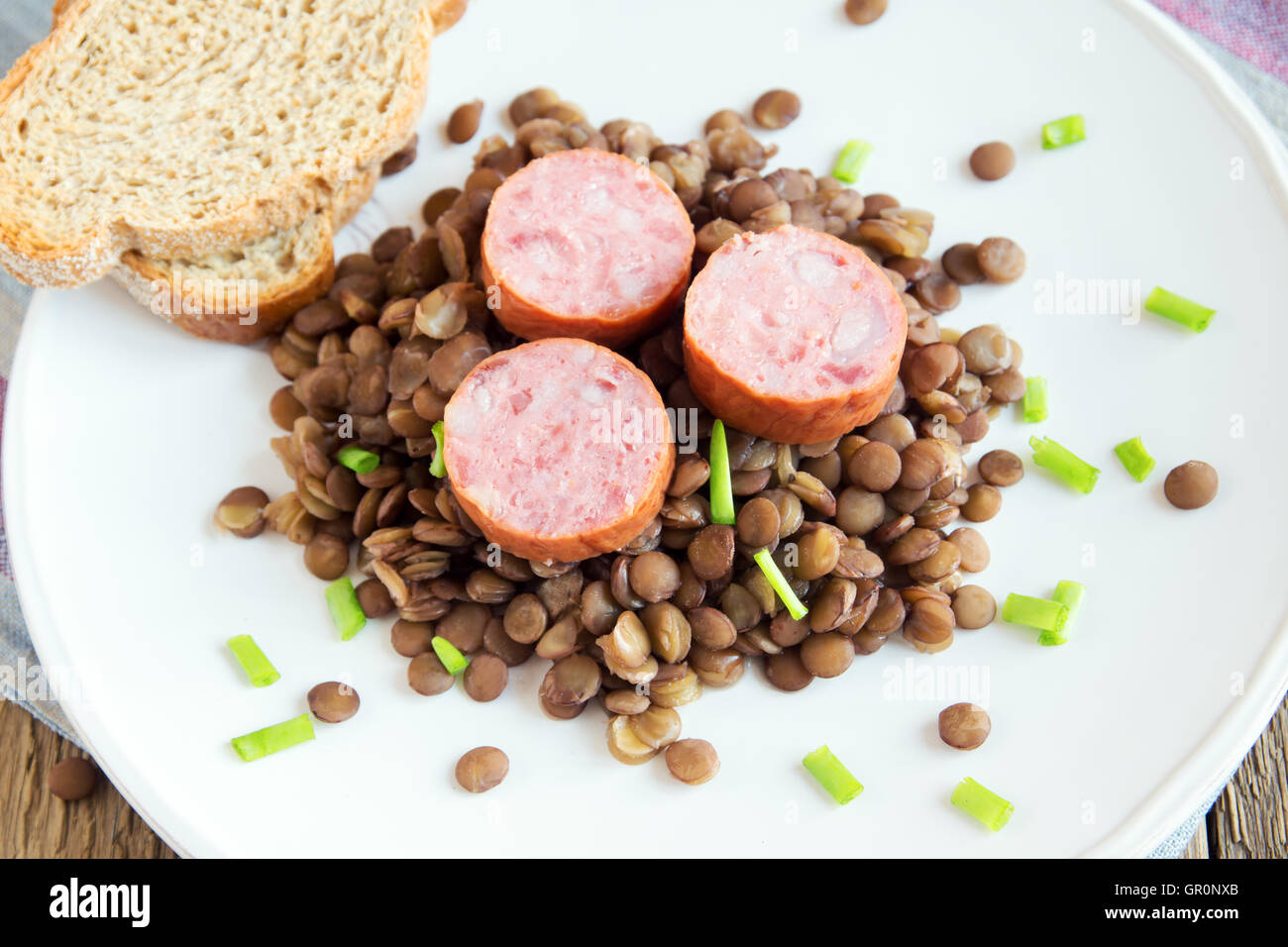 Green lentil with pork sausage (cotechino) on white plate Stock Photo