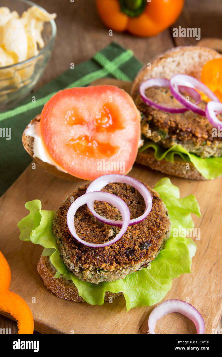 Vegetarian lentil burger with vegetables on wooden cutting board Stock