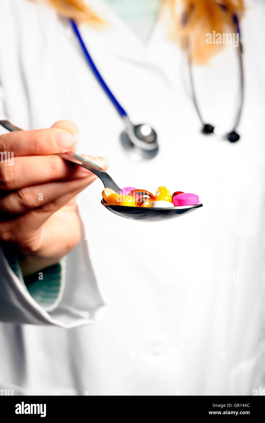 doctor handing a spoon of pills, nutritional supplements Stock Photo