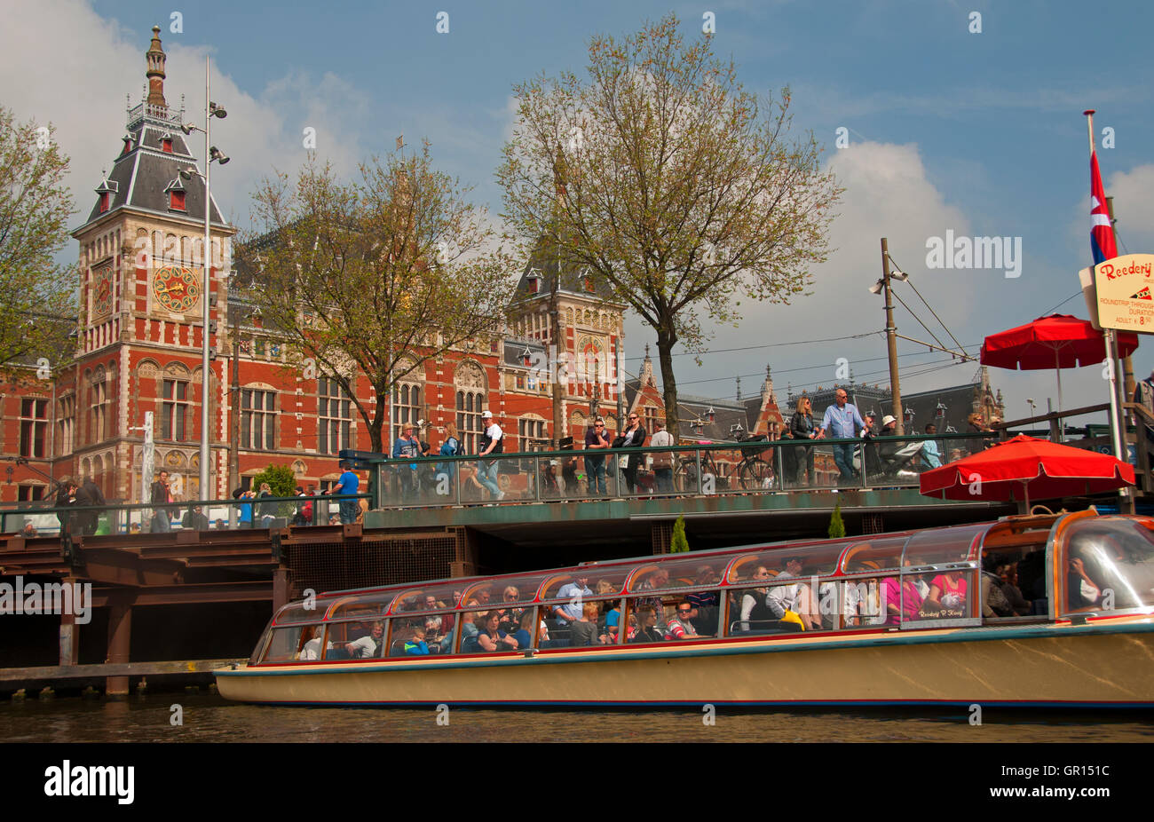 Canal Tour Boat passes in front of Centraal Station, Amsterdam, Holland Stock Photo