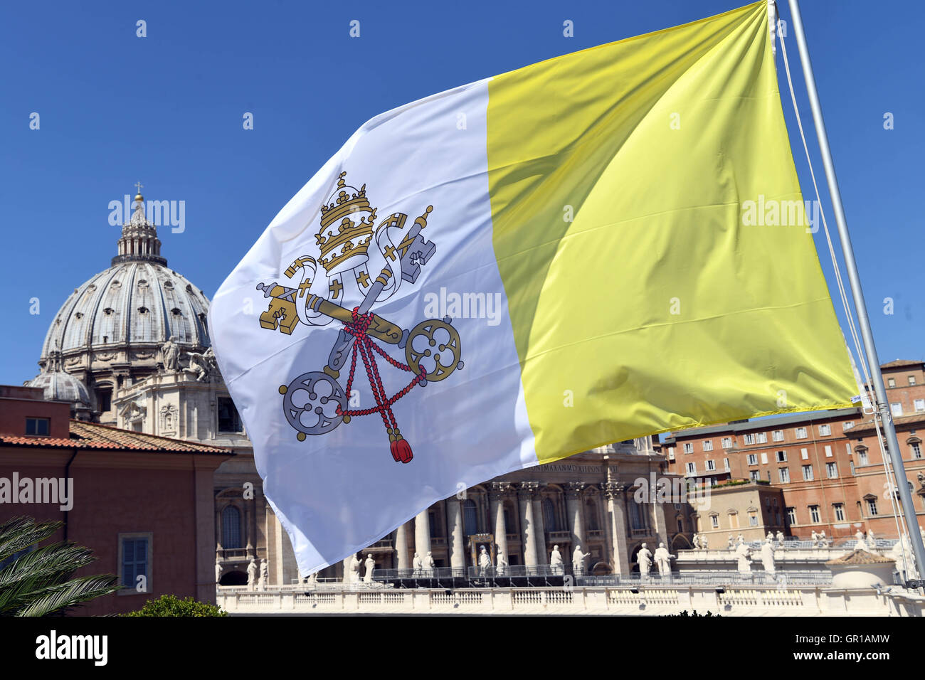 A flag with the coat of arms of Vatican City waves in Vatican City, 02 September 2016. St. Peter's Basilica can be seen in the background. Photo: ULI DECK/dpa Stock Photo
