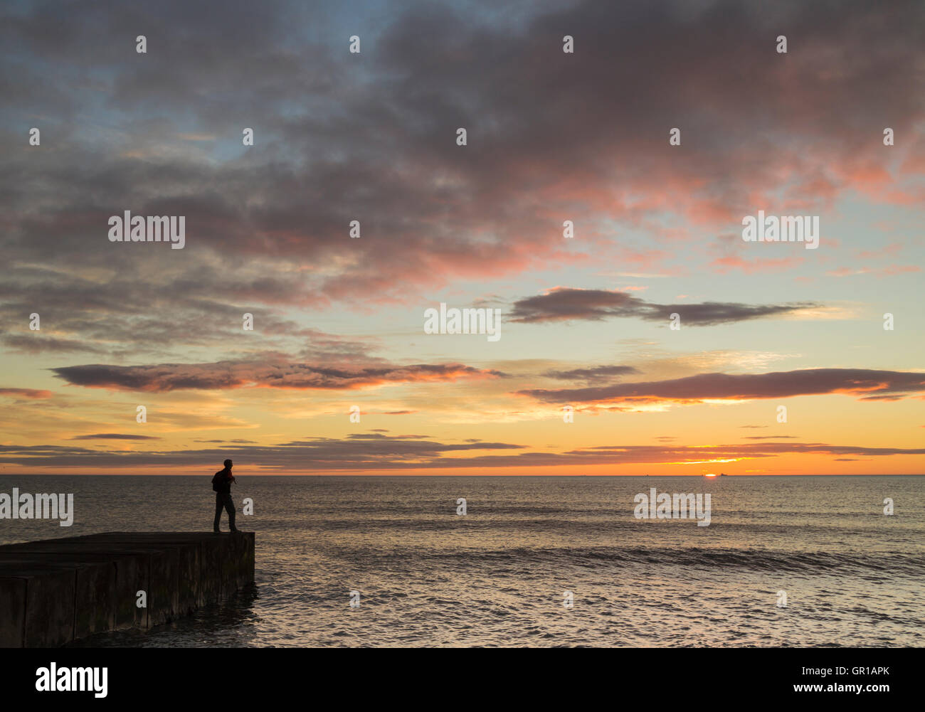 Seaton Carew, north east England, UK, 6th, September, 2016. Weather: A hiker on The England Coast Path at Seaton Carew watches a glorious sunrise over the North sea on a beautiful Tuesday morning on the north east coast. Temperatures already in the high teens just after sunrise Credit:  Alan Dawson News/Alamy Live News Stock Photo