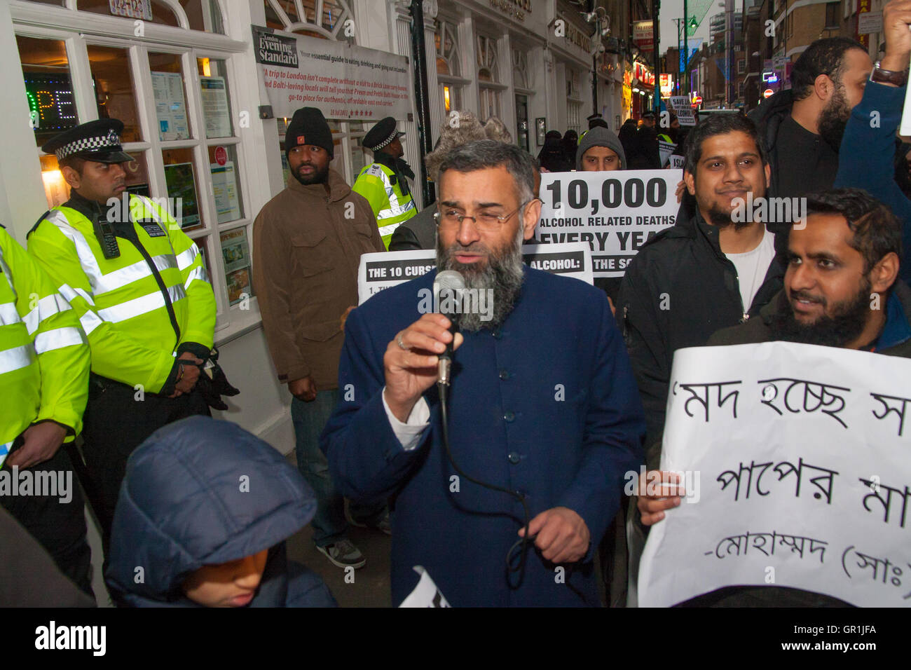 Brick Lane, London, December 13th 2013. Anjem Choudary, with microphone, leads his  'Sharia Project' as they demonstrate in Brick Lane against the consumption of Alchohol, blaming society's ills on drinking, and demanding that strict Sharia law be imposed to replace 'man-made' laws. Credit:  Paul Davey/Alamy Live News Stock Photo