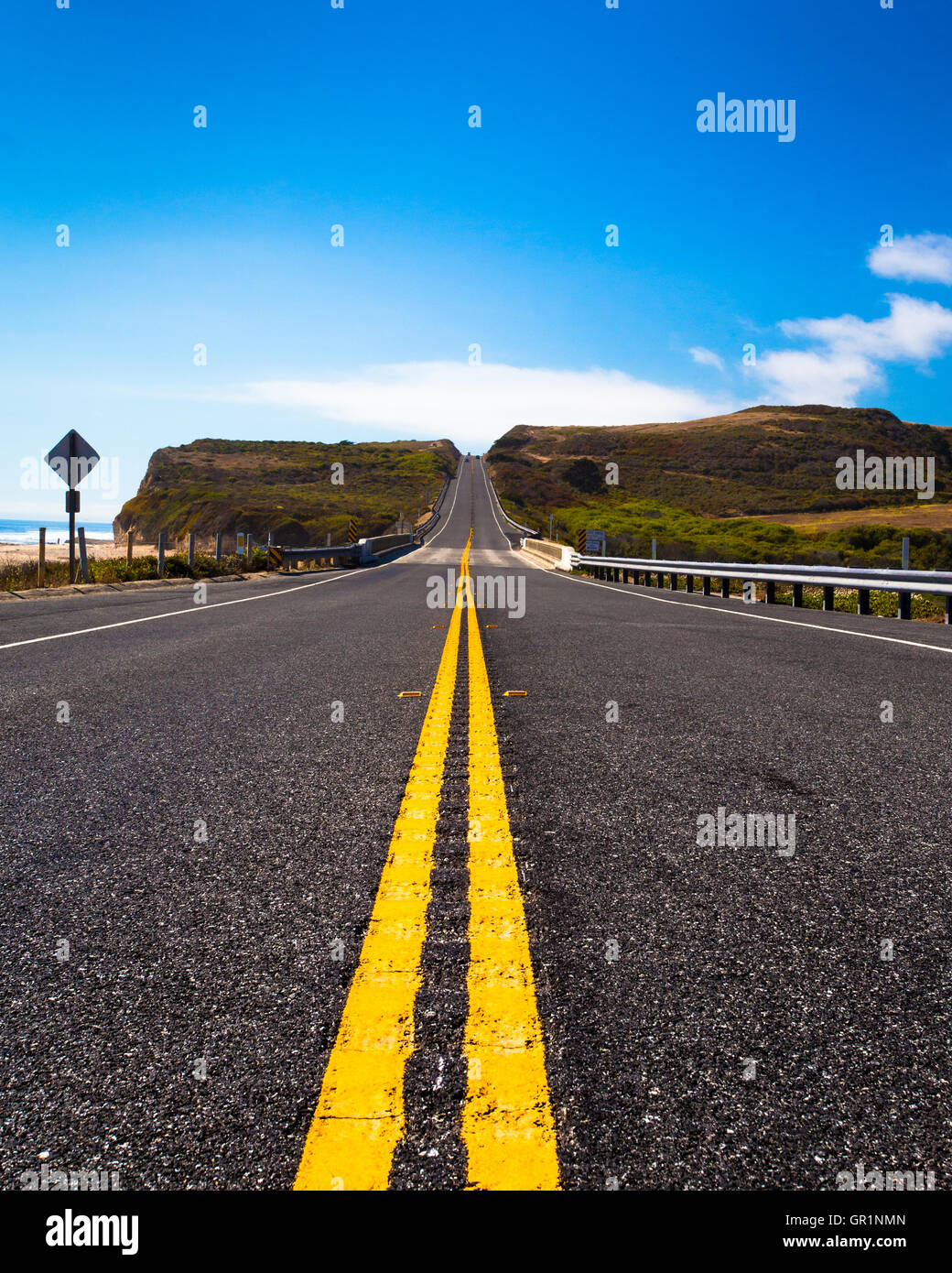 Yellow road dividing lines on road along the California Coast Stock Photo