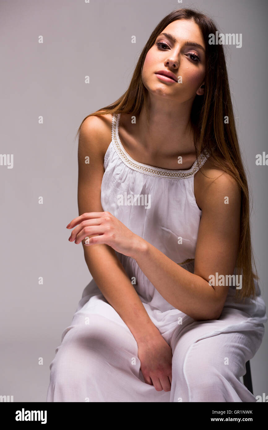 Pretty young woman with long hair in white dress in studio Stock Photo ...
