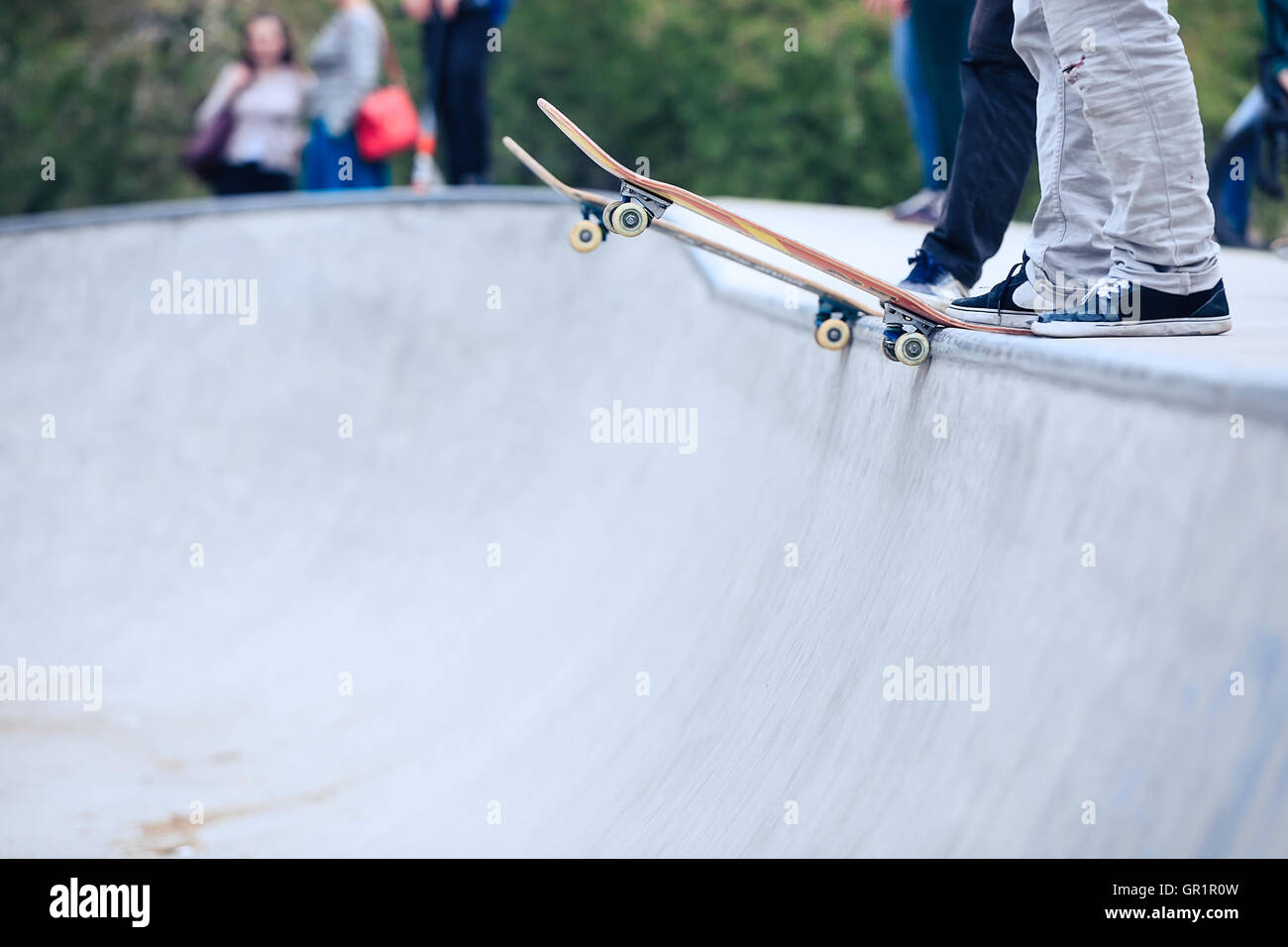 Skateboarder standing on a ramp in skate park ready to ride skate board ...