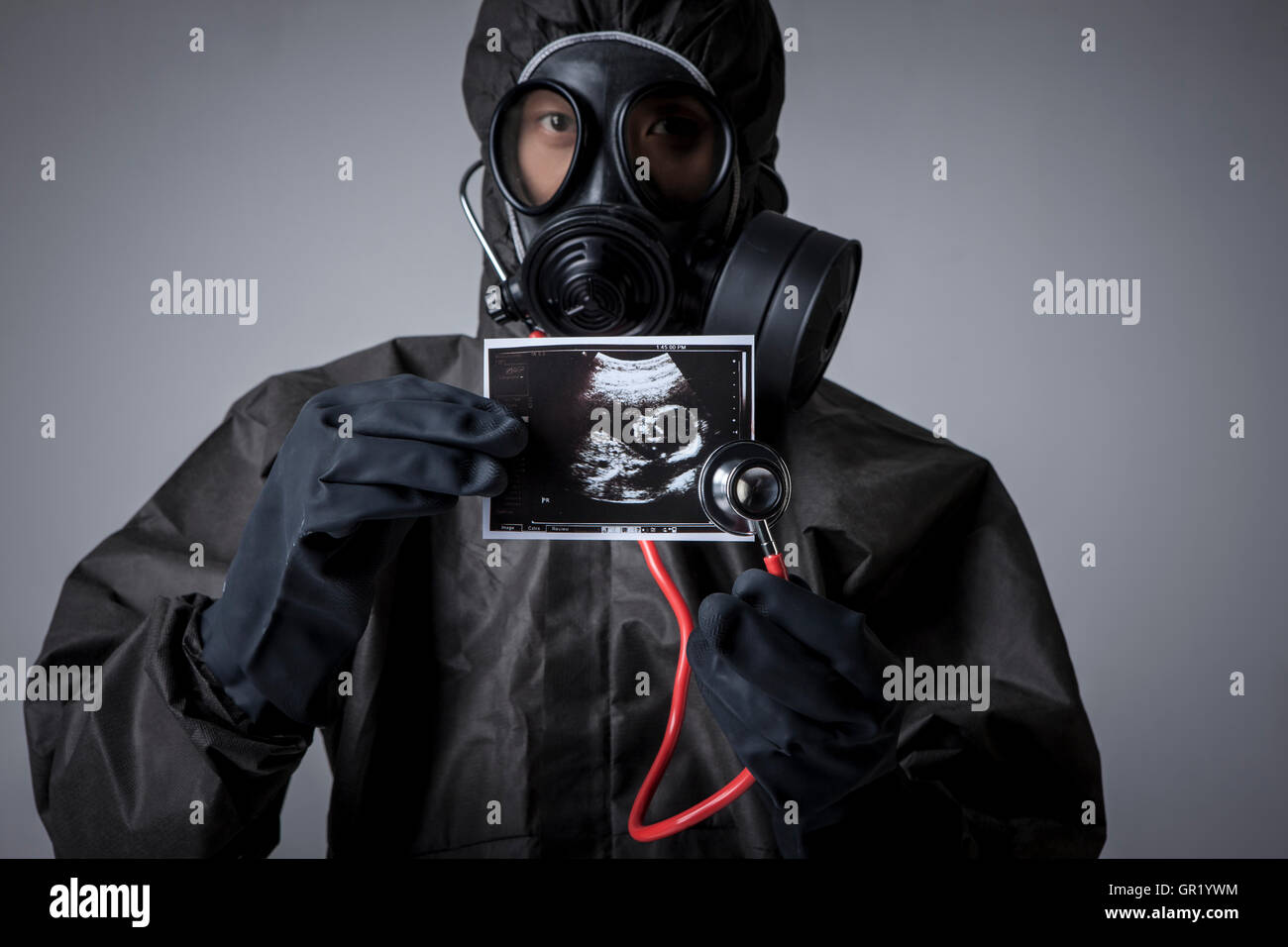 Portrait of man wearing gas mask and black clothes holding a sonogram Stock Photo