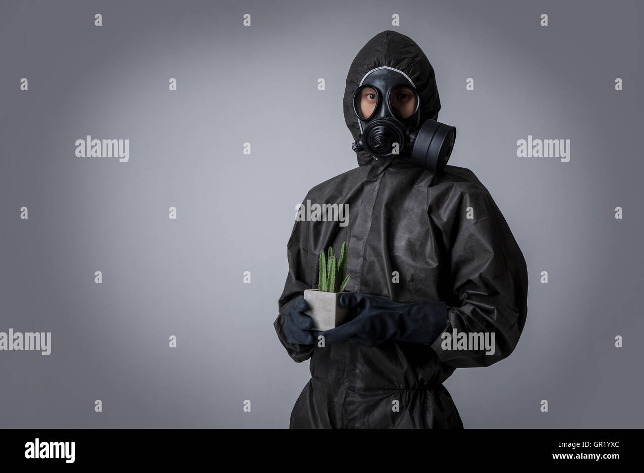 Young man wearing gas mask and black clothes holding planted pot Stock Photo
