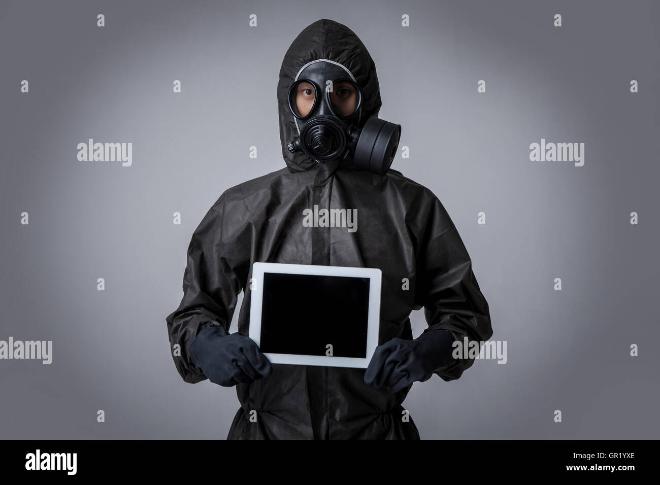 Young man wearing gas mask and black clothes holding a tablet Stock Photo