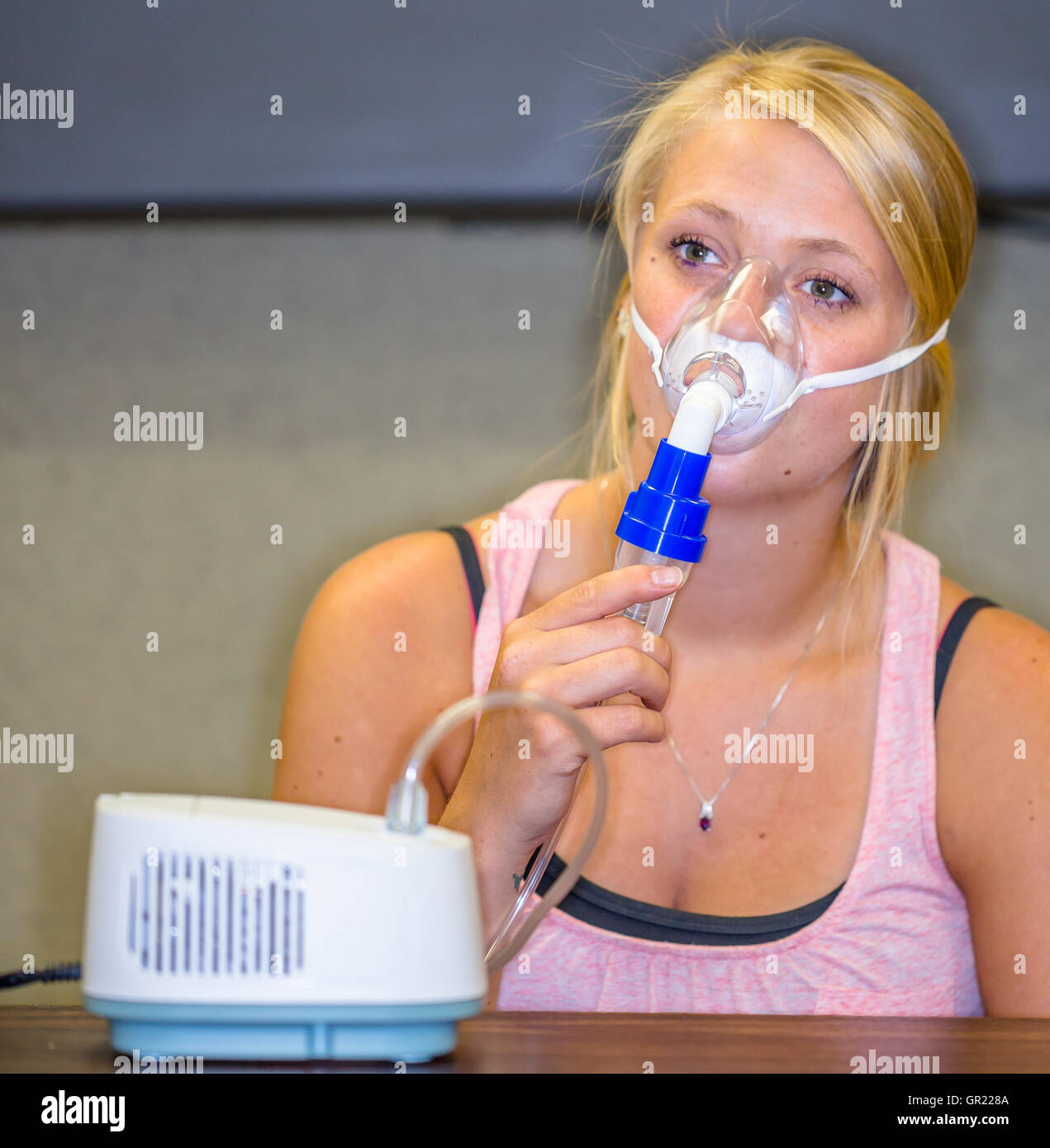 A young woman using a nebulizer aerosol mask and compressor Stock Photo
