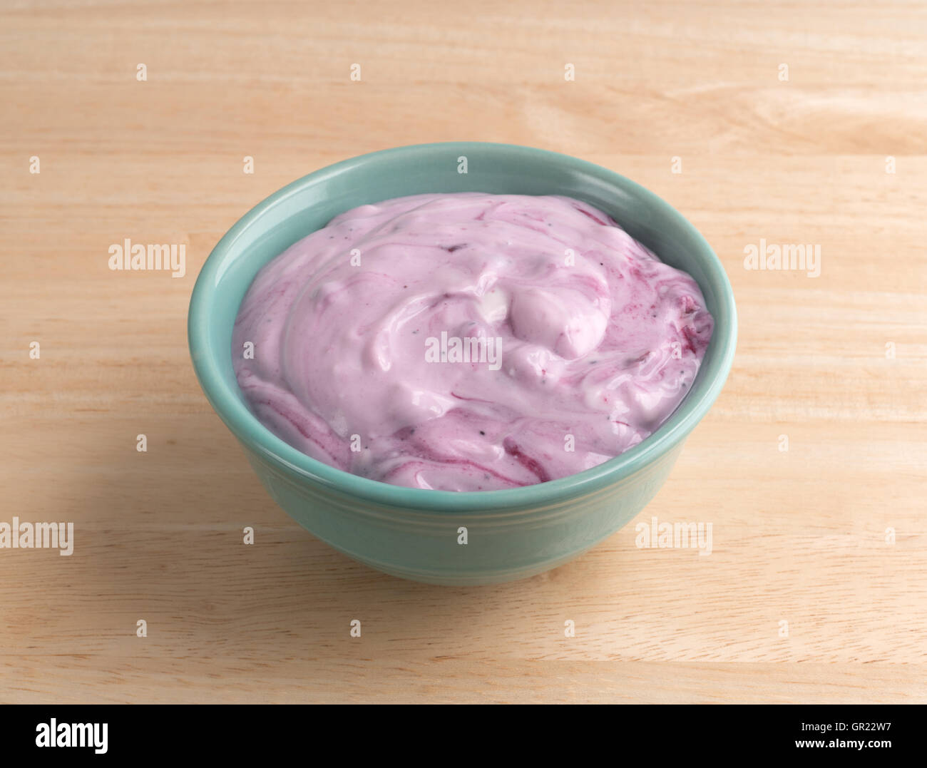 A bowl with a serving of blueberry gourmet yogurt on a wood table. Stock Photo