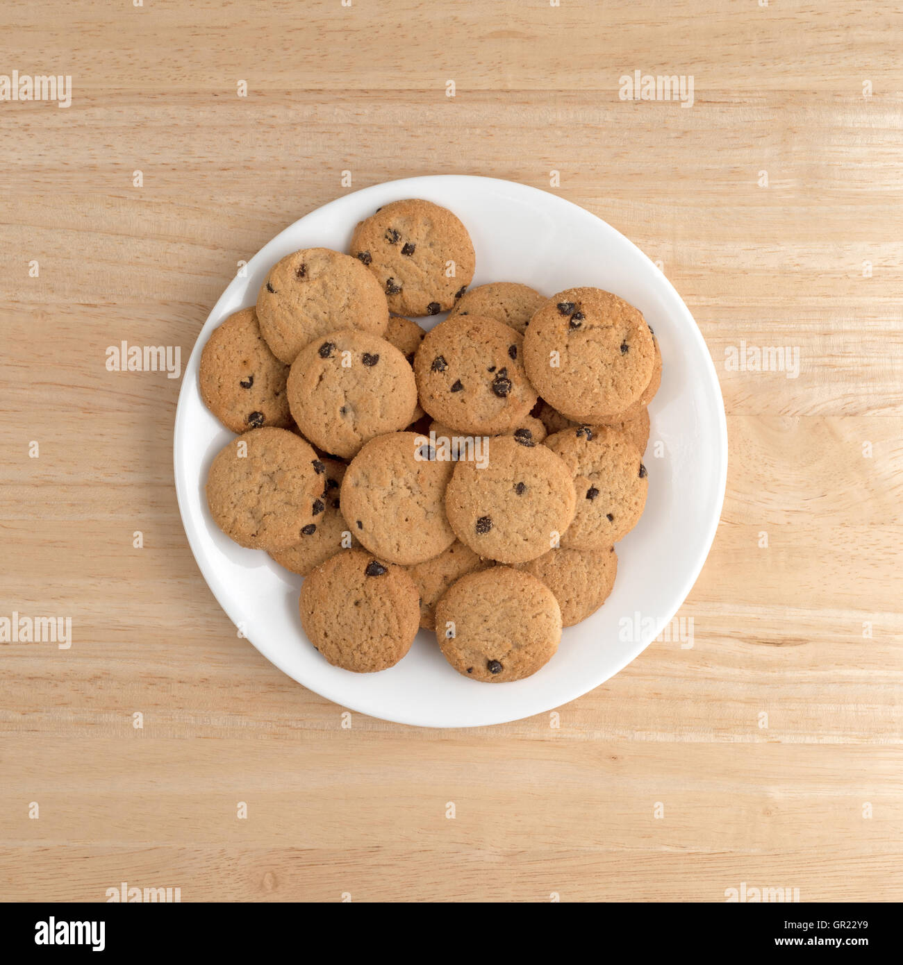 Top view of vanilla chocolate chip cookies on a white plate atop a wood table. Stock Photo