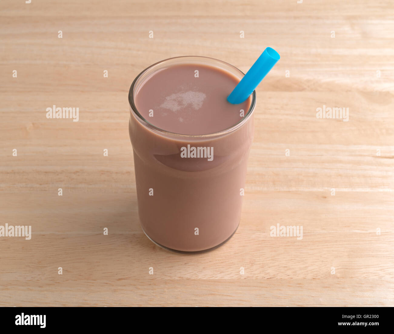 A glass of chocolate milk with a straw on a wood table. Stock Photo