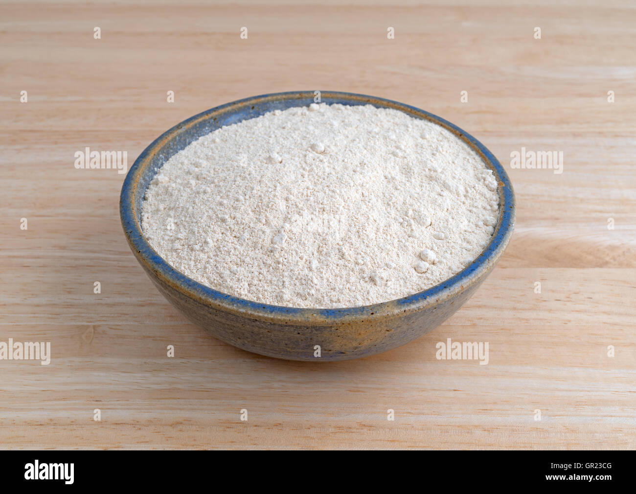 A bowl filled with quinoa flour on a wood table. Stock Photo